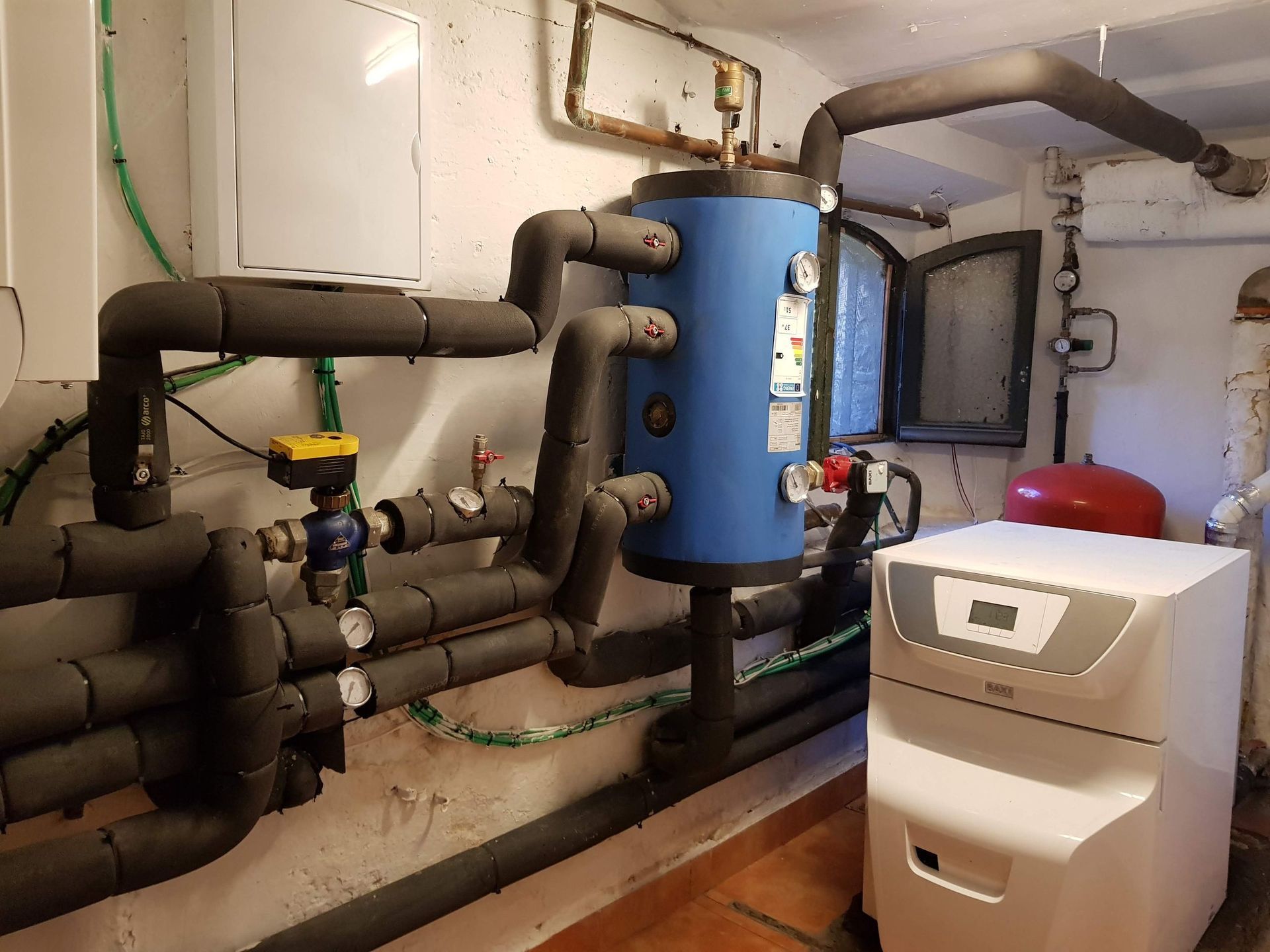 Una habitación con muchas tuberías y un calentador de agua azul.
