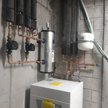 Una habitación con una caldera y tuberías en la pared.
