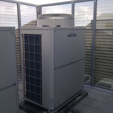 Un gran acondicionador de aire blanco está situado encima de un techo.