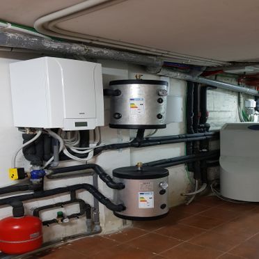 Una habitación con muchas tuberías y una caldera en la pared.