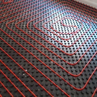 Un primer plano de un sistema de calefacción por suelo radiante rojo y negro.