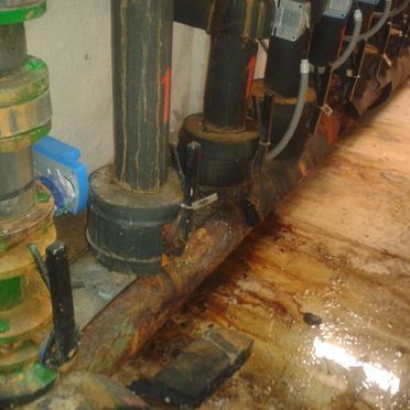 Una habitación sucia con muchas tuberías y cables.