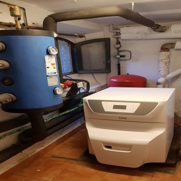 Una caldera está en una habitación al lado de un tanque azul.