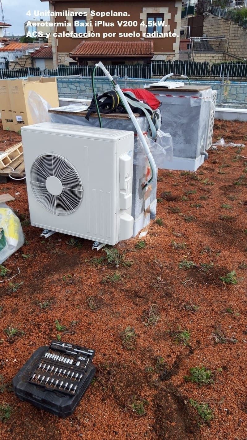 Un acondicionador de aire blanco está situado encima de un campo de tierra.