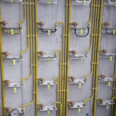 Una pared con un montón de tubos amarillos y estantes.