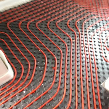 Un primer plano de un sistema de calefacción por suelo radiante rojo y negro.