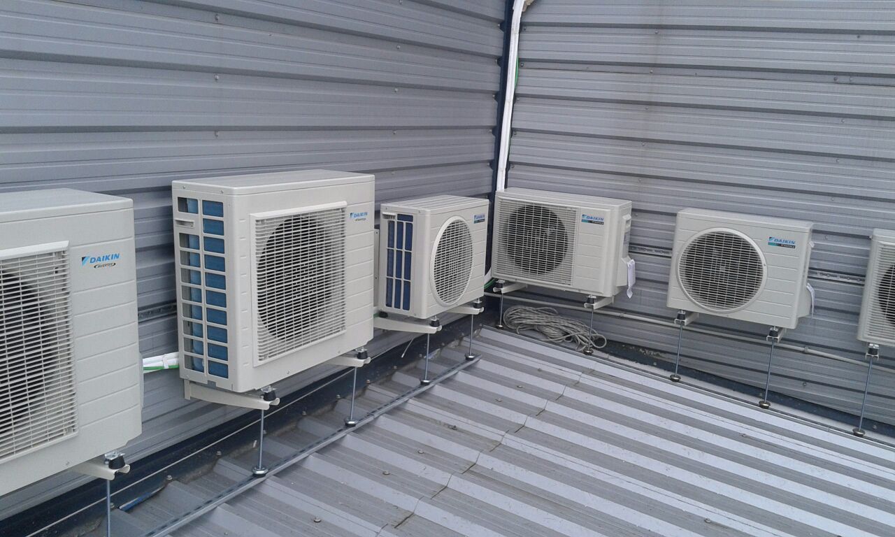 Una fila de aparatos de aire acondicionado están alineados en el costado de un edificio.