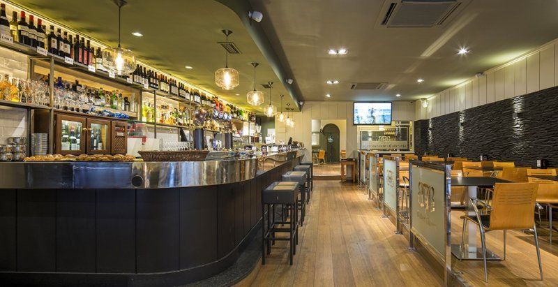 Un restaurante con una barra larga y mesas y sillas.