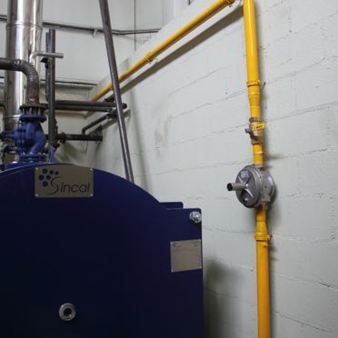 Una caldera dincal azul está al lado de una tubería amarilla.