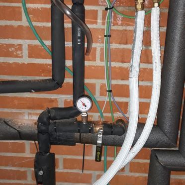 Una pared de ladrillos con un montón de tuberías conectadas a ella.