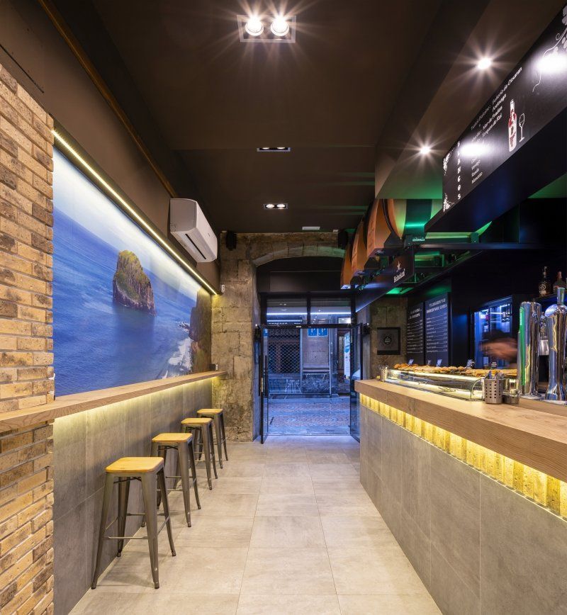 Un largo pasillo con taburetes y un cuadro grande en la pared.