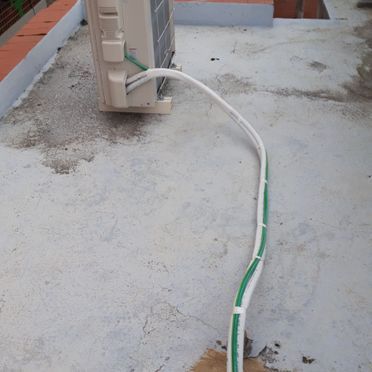 Un acondicionador de aire blanco con una manguera verde conectada a él.