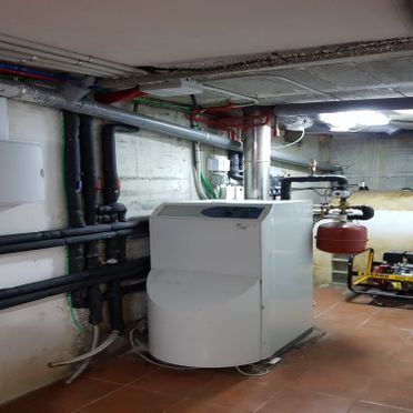 Una gran caldera blanca está en una habitación con tuberías.