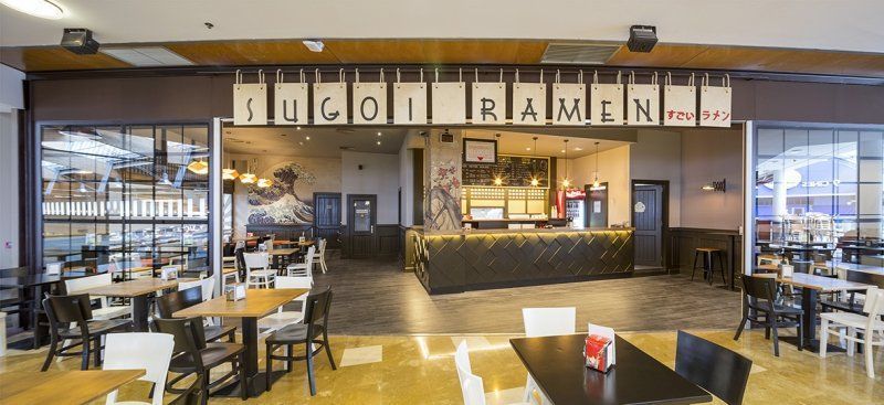 Un restaurante con mesas y sillas en un centro comercial.