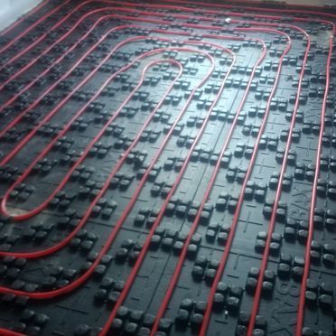 Un primer plano de un suelo radiante con tuberías rojas.