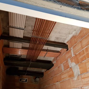 Una habitación con una pared de ladrillos y tuberías de cobre colgando del techo.