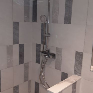 Una ducha con un cabezal de ducha y un grifo en un baño.