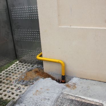 Un tubo amarillo está conectado al costado de un edificio.