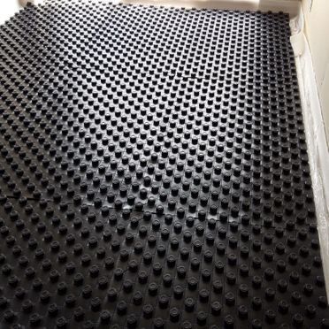 Un primer plano de una alfombra negra con agujeros.