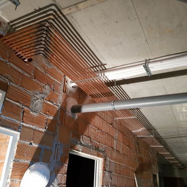 Una pared de ladrillos con tuberías colgando del techo.