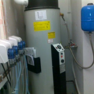 Un calentador de agua está en una habitación al lado de un tanque azul.