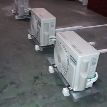 Dos aparatos de aire acondicionado están sobre un suelo de hormigón.