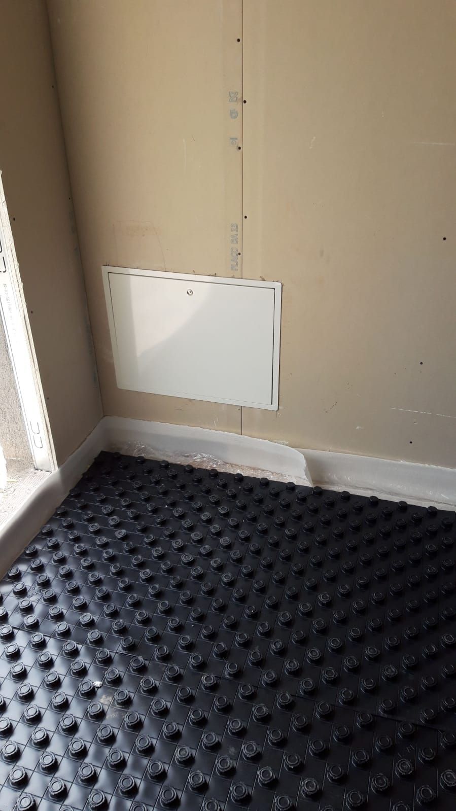 Una habitación con suelo negro y pared blanca.