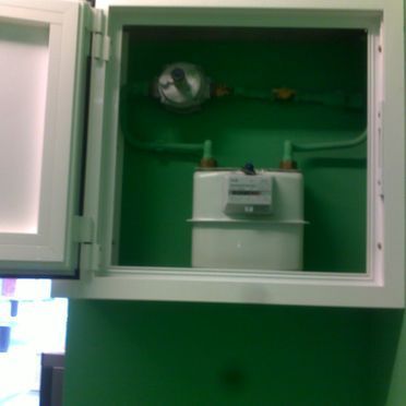 Un medidor de gas en un armario verde con la puerta abierta.