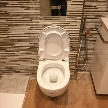 Un inodoro en un baño con la tapa levantada.