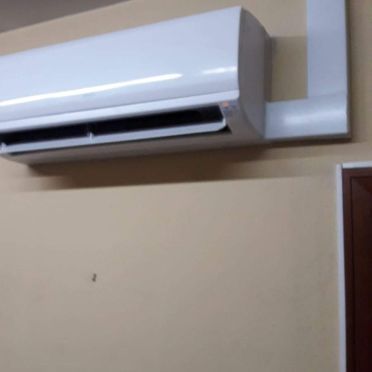 Un acondicionador de aire blanco está colgado en una pared al lado de una puerta.