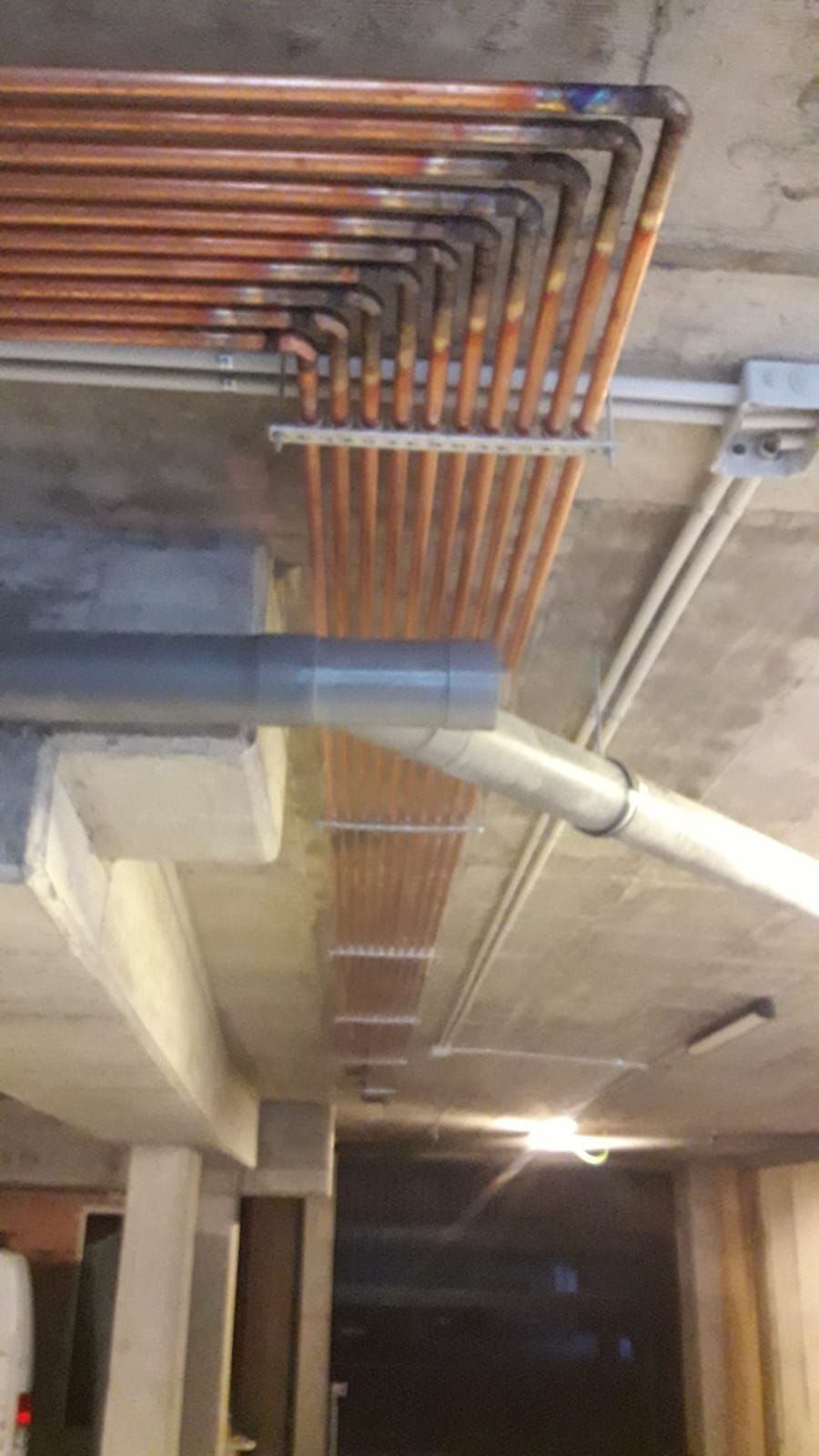 Un montón de tubos de cobre cuelgan del techo de un edificio.