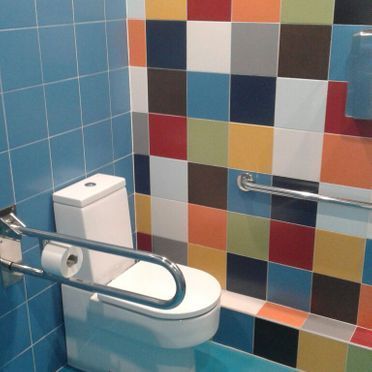 Un baño con azulejos de colores y un inodoro.