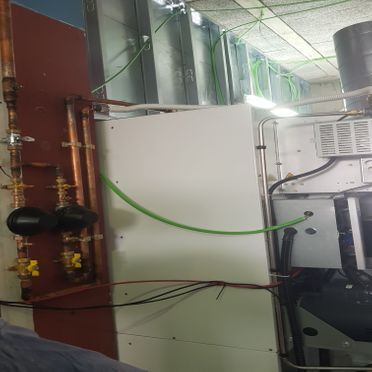 Una manguera verde está conectada a una tubería de cobre en una habitación.