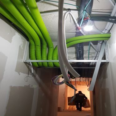 Un hombre camina por un pasillo con tuberías verdes colgando del techo.