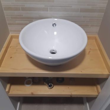 Un fregadero blanco se encuentra encima de un mostrador de madera.