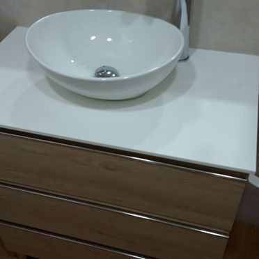 Un lavabo blanco se encuentra sobre una encimera blanca.