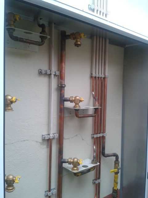 Una pared con tuberías de cobre y válvulas de latón.