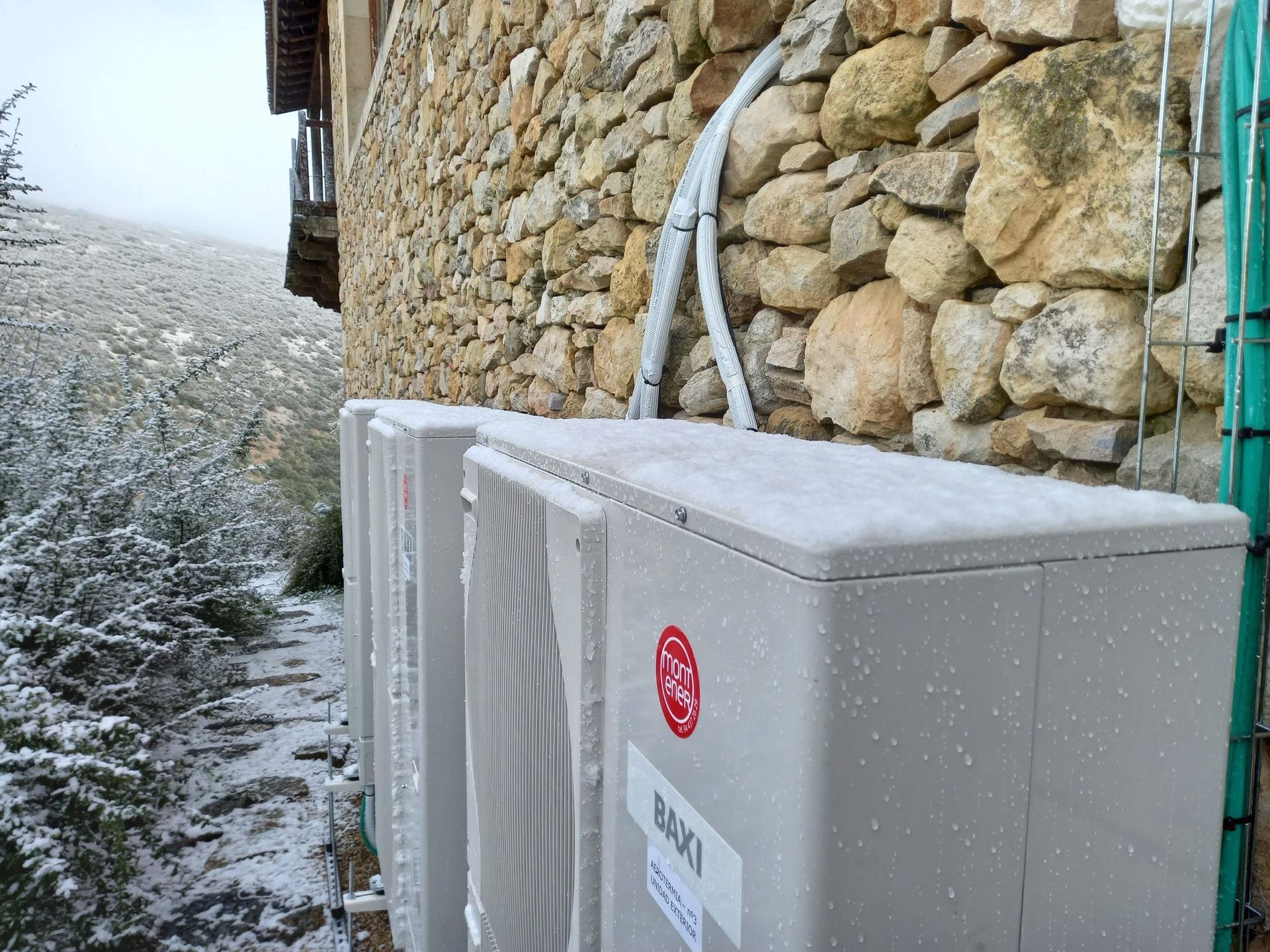 Dos acondicionadores de aire LG están ubicados uno al lado del otro frente a una pared de piedra.