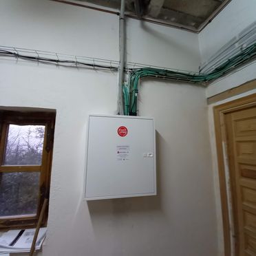 Una caja blanca está colgada en una pared al lado de una ventana.