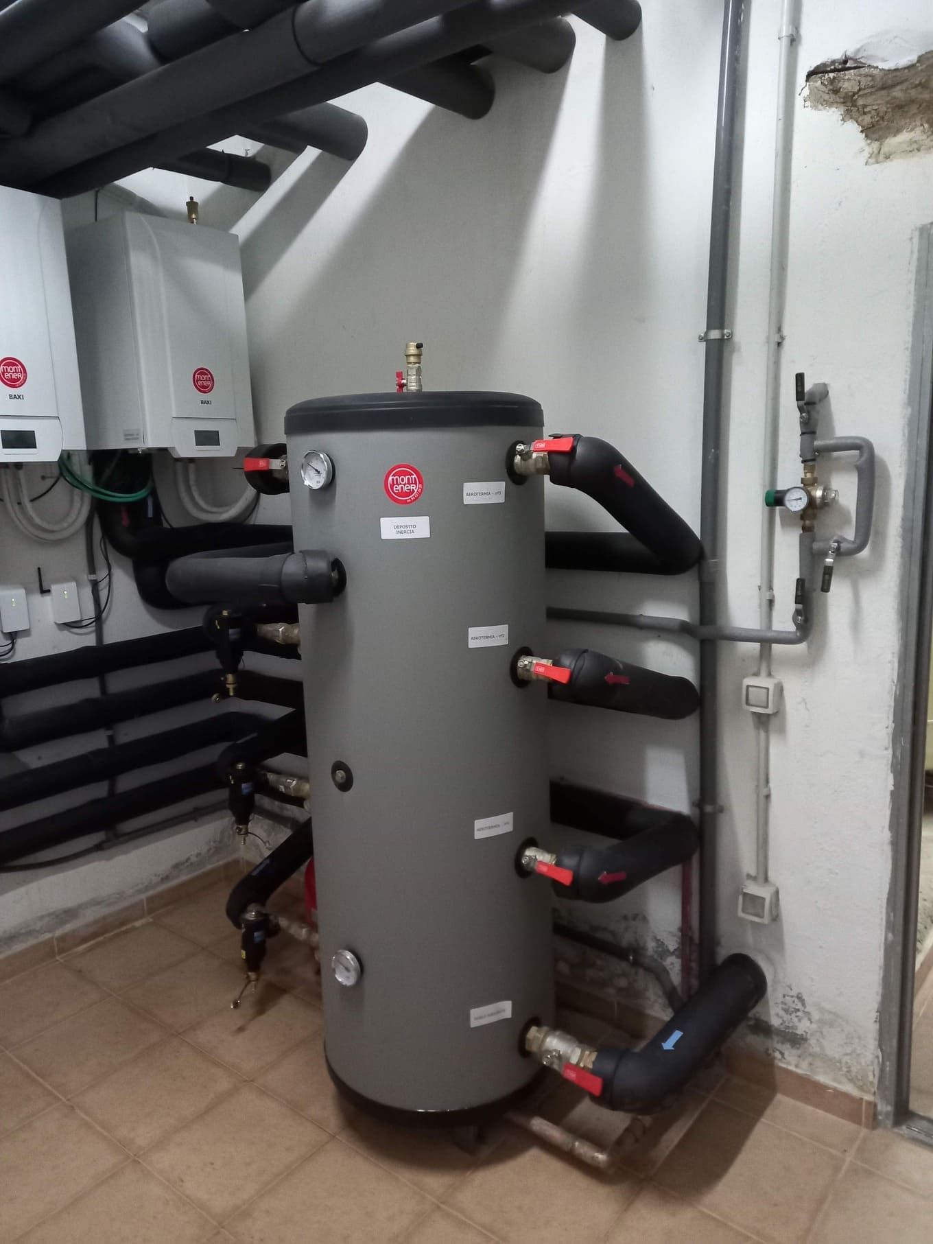 Un gran tanque gris está sentado en una habitación al lado de una pared.