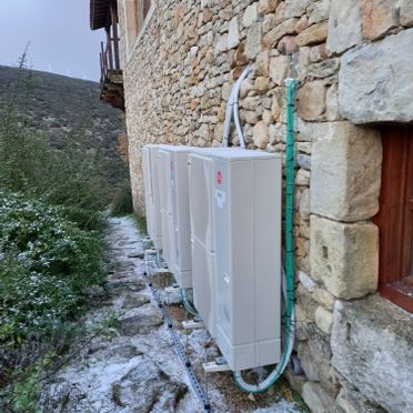 Una fila de aparatos de aire acondicionado están instalados en el lateral de un edificio de piedra.