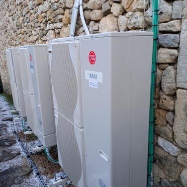 Una fila de aparatos de aire acondicionado están alineados contra una pared de piedra.