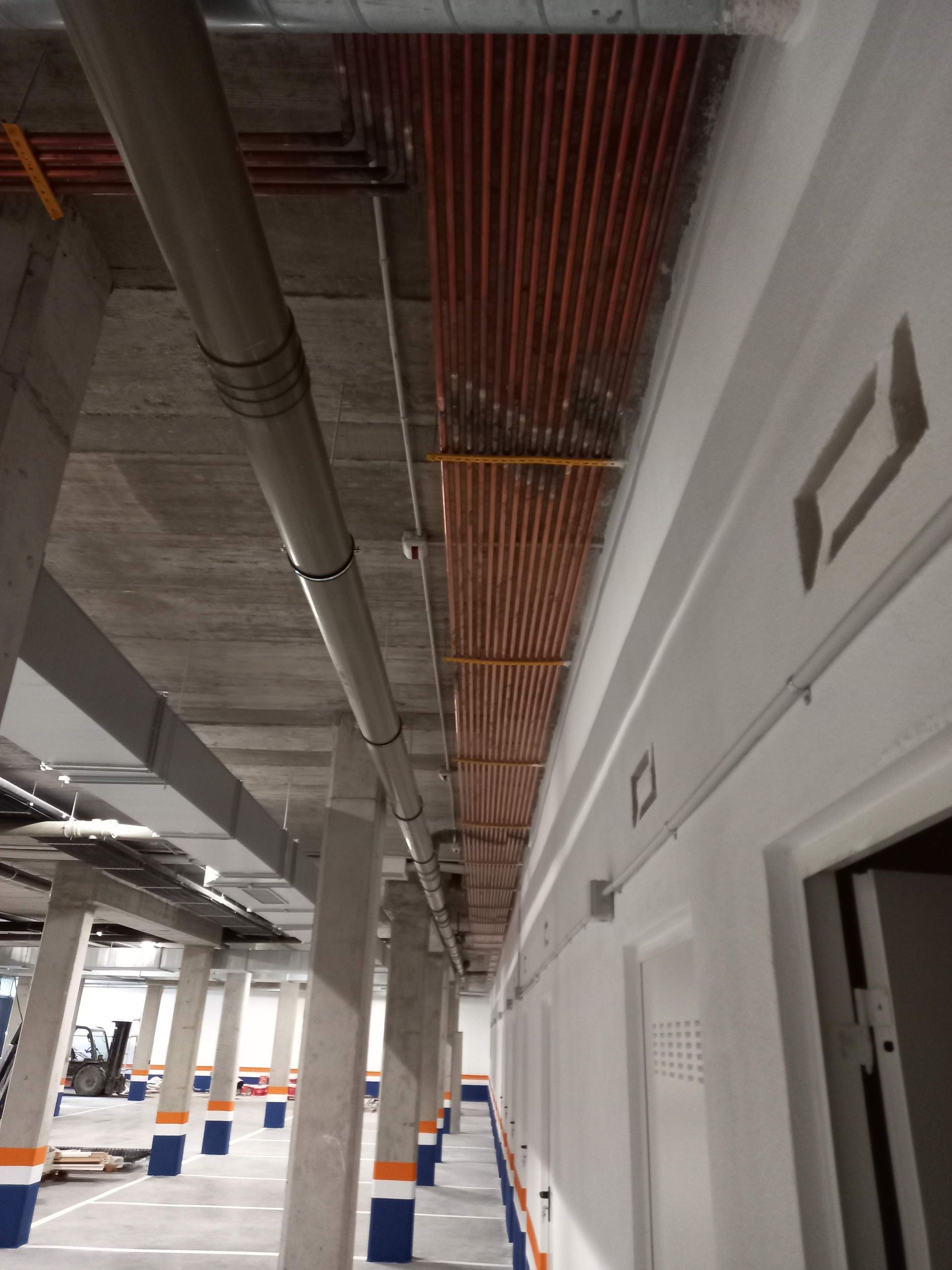 Un largo pasillo en un edificio con tuberías colgando del techo.