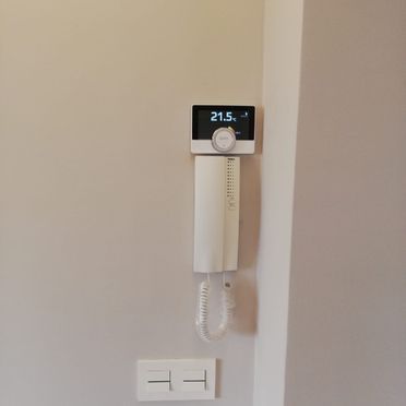 Un teléfono blanco está colgado en una pared al lado de un termostato.