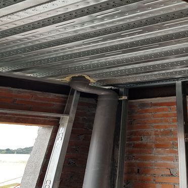 Un techo de metal con una tubería que sale de él en una habitación con paredes de ladrillo.