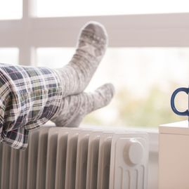 Una persona está acostada sobre un radiador con los pies en alto.