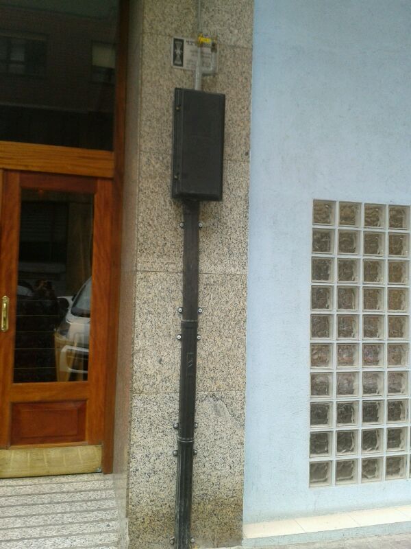 Un tubo negro cuelga del costado de un edificio al lado de una puerta.