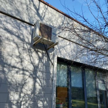 Un gran acondicionador de aire está montado en el lateral de un edificio.