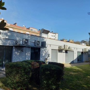 Un gran edificio blanco con muchos aparatos de aire acondicionado a un lado.