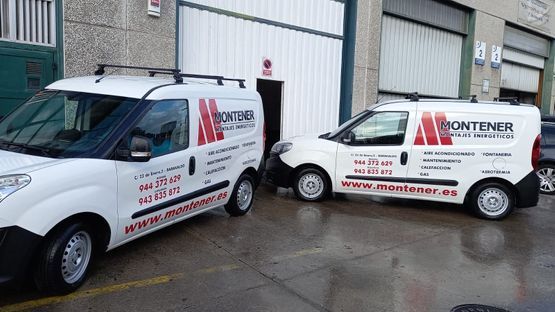 Dos furgonetas blancas están estacionadas delante de un edificio.